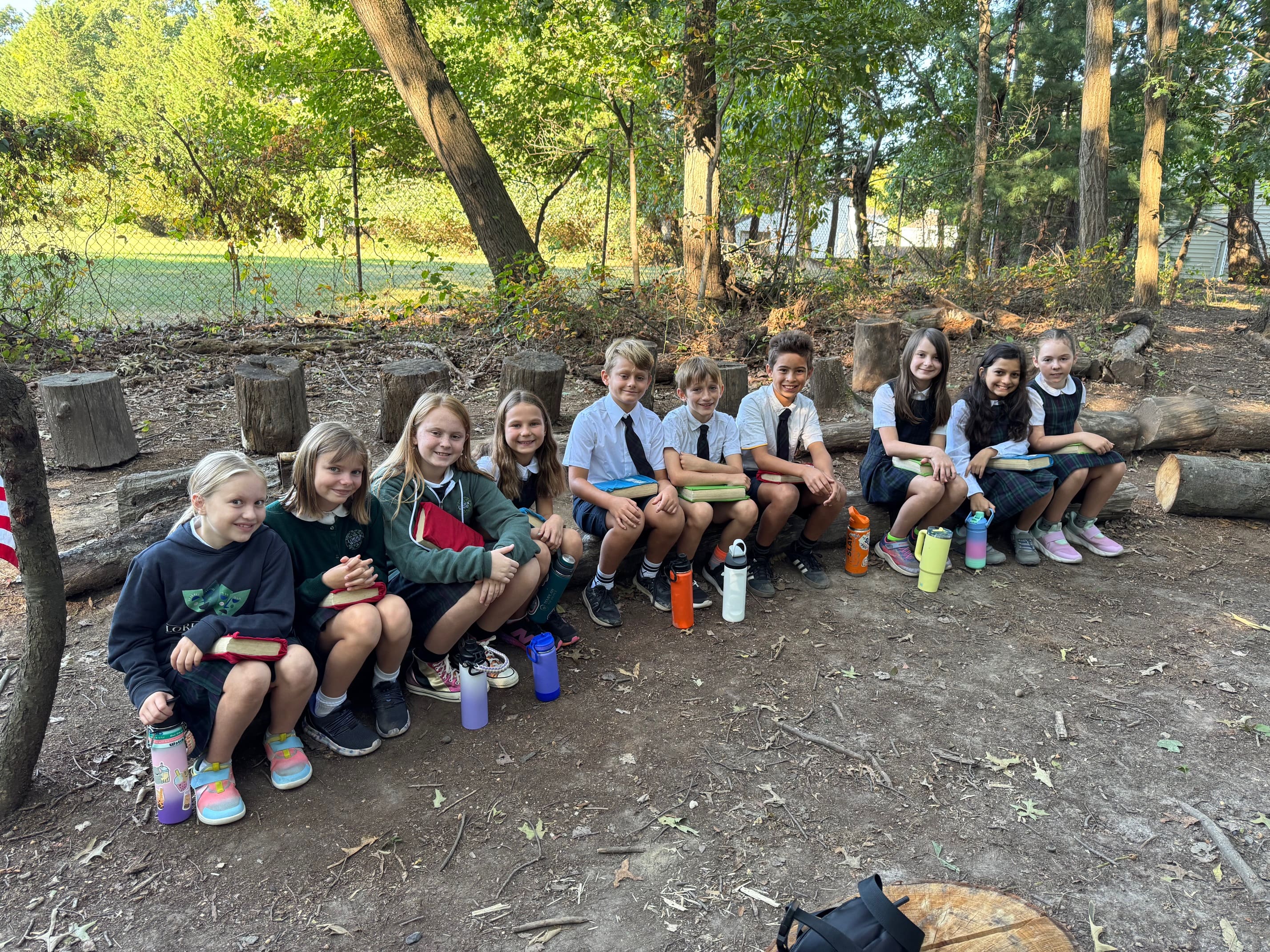 students outside sitting on logs